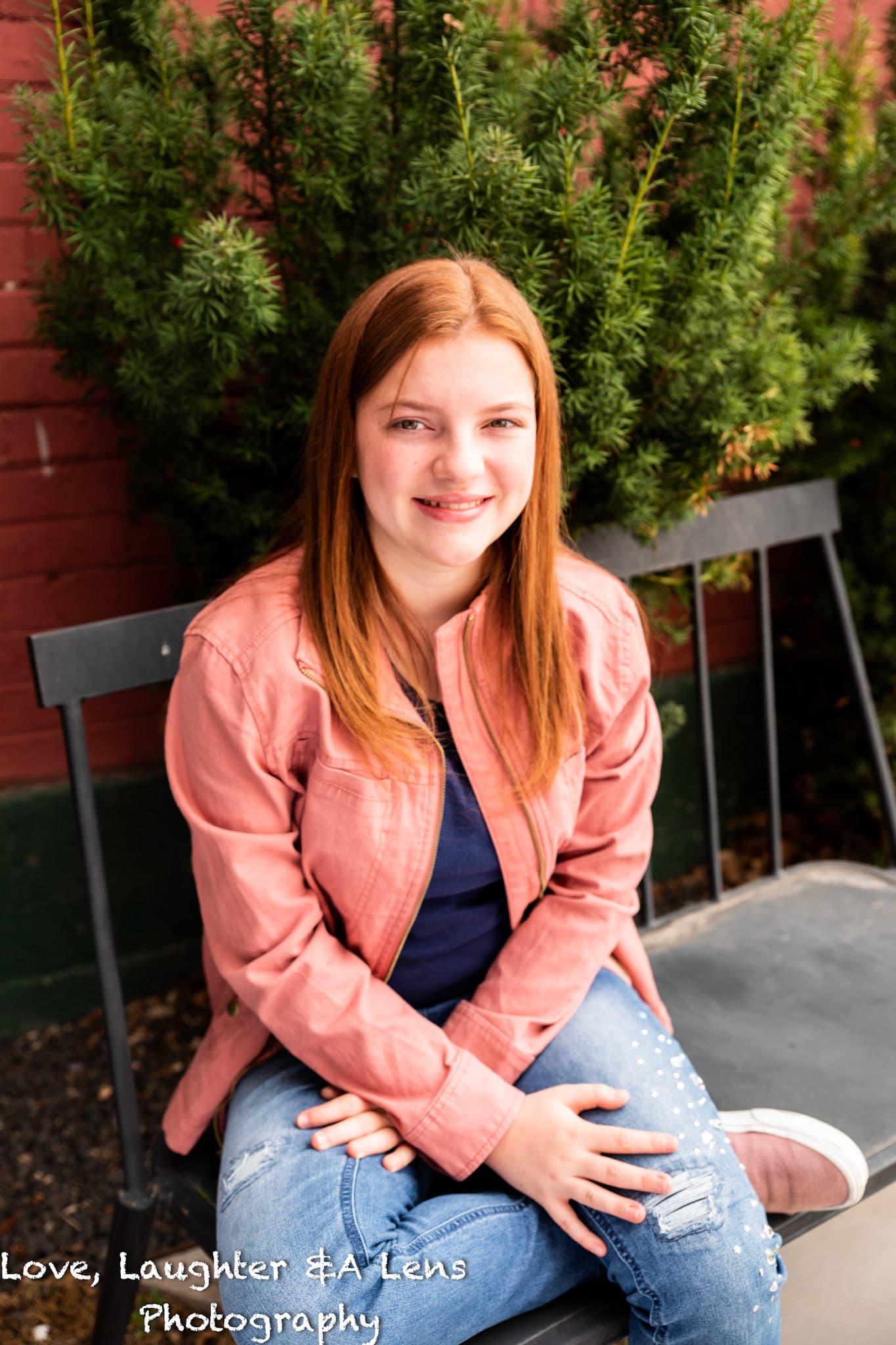 Child in a pink jacket sitting on a bench