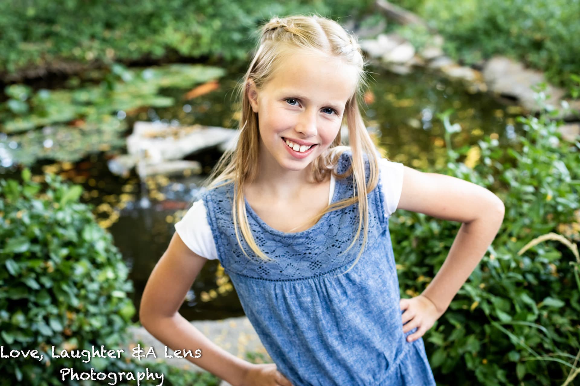 Child in a blue dress smiling in a garden