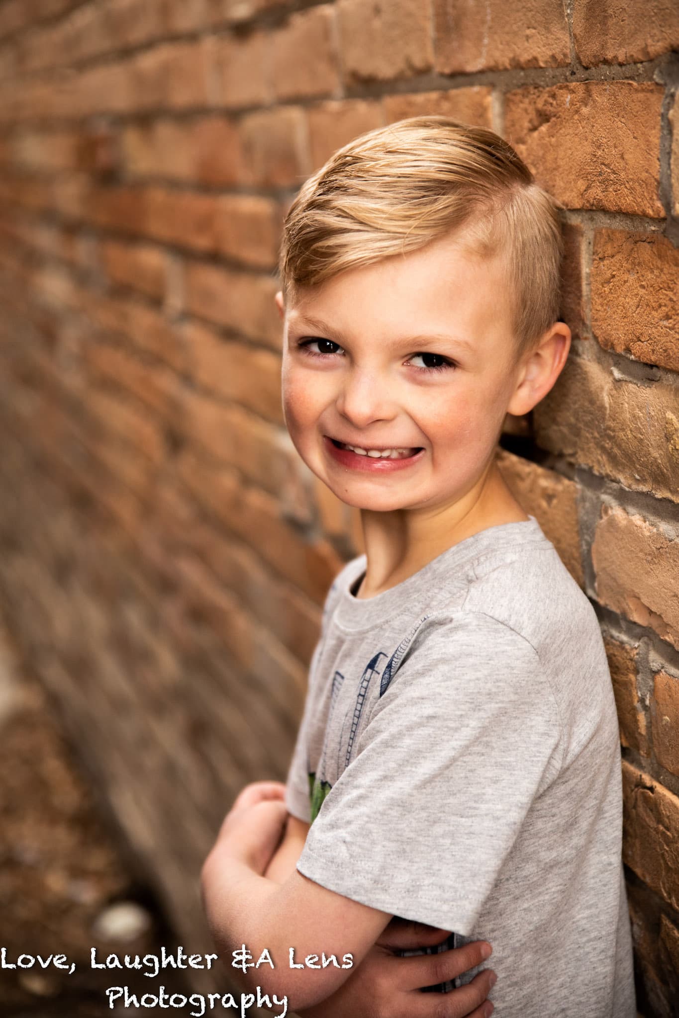 Smiling child leaning on a brick wall