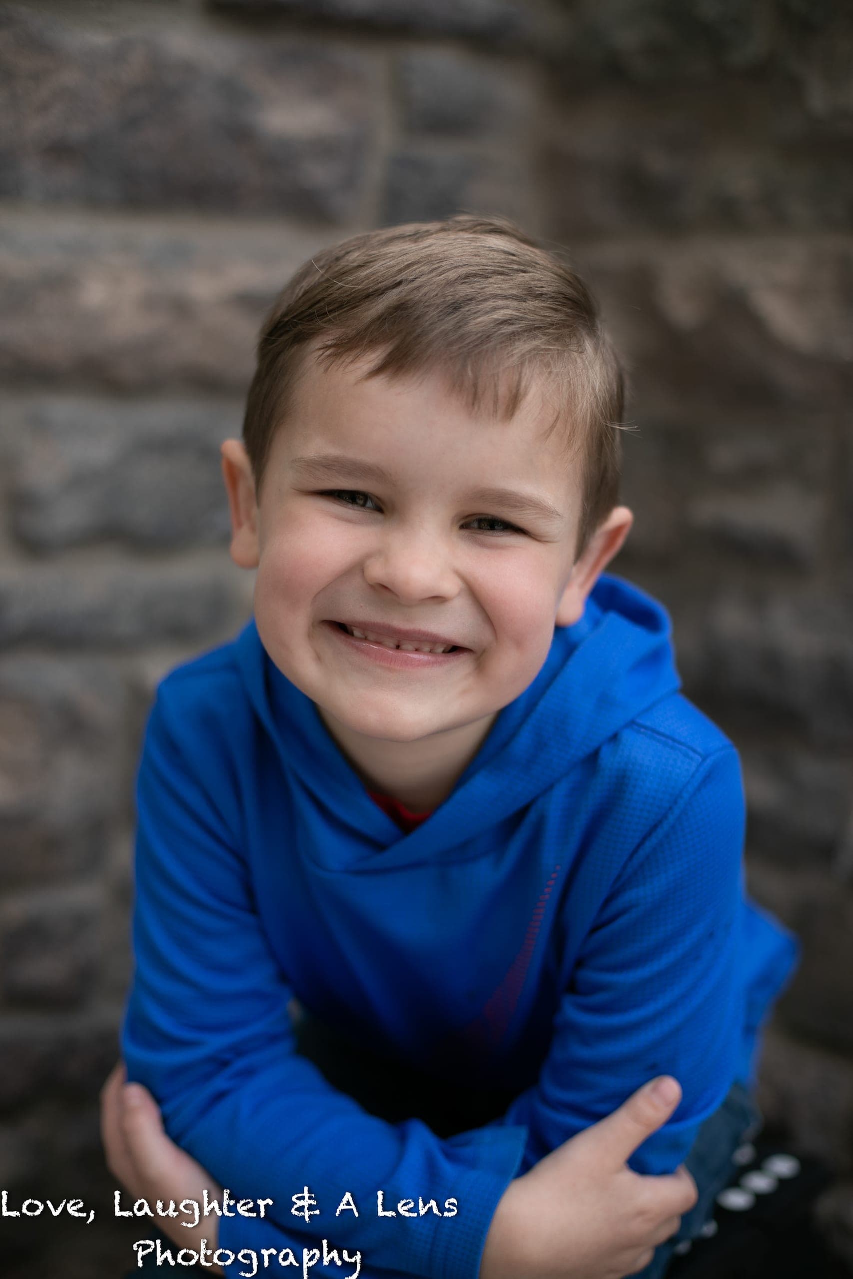 Child in a blue hoodie smiling at the camera