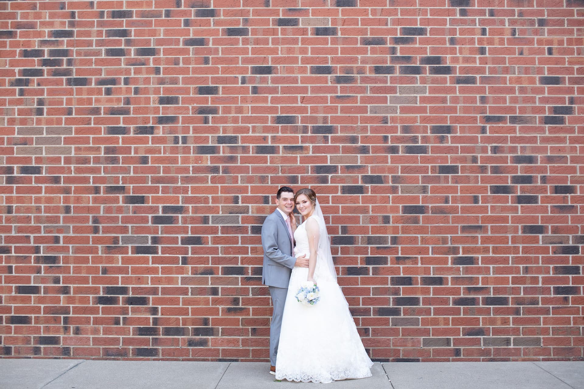 Bride and groom in front of a red brick wall