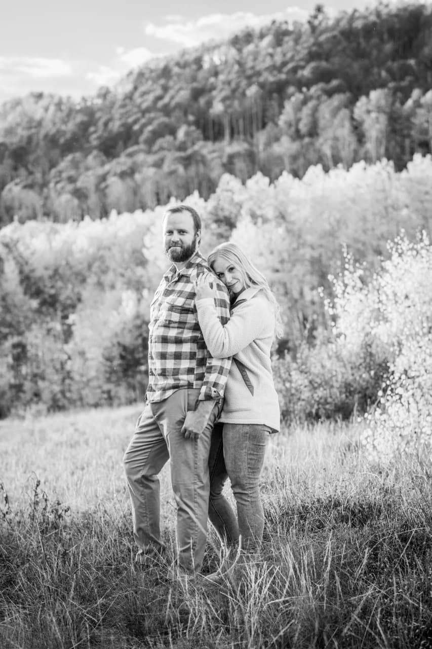 Black-and-white photo of an engaged couple in the aspens