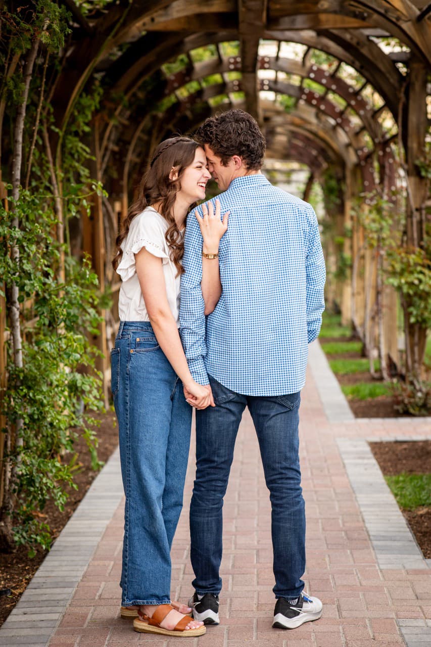 Engaged couple under a wooden arbor