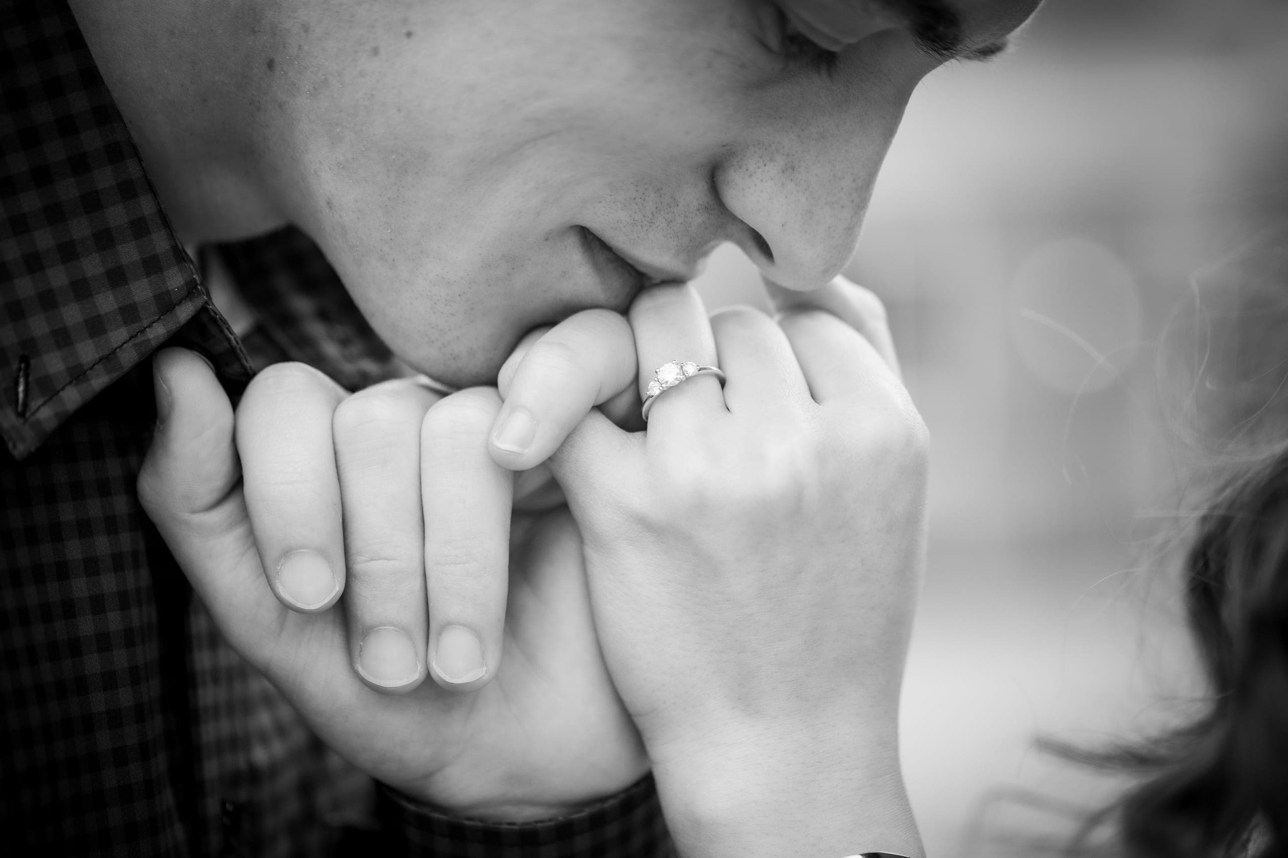 Kiss on a hand wearing an engagement ring, in black and white