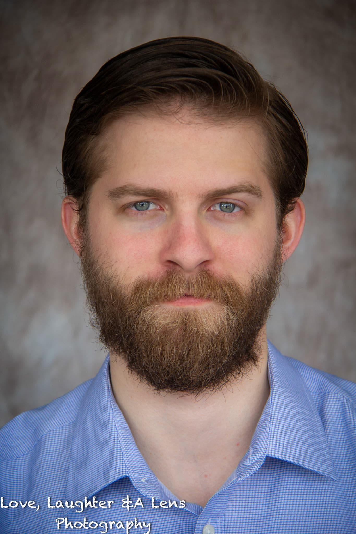Headshot of a bearded man in a blue collared shirt