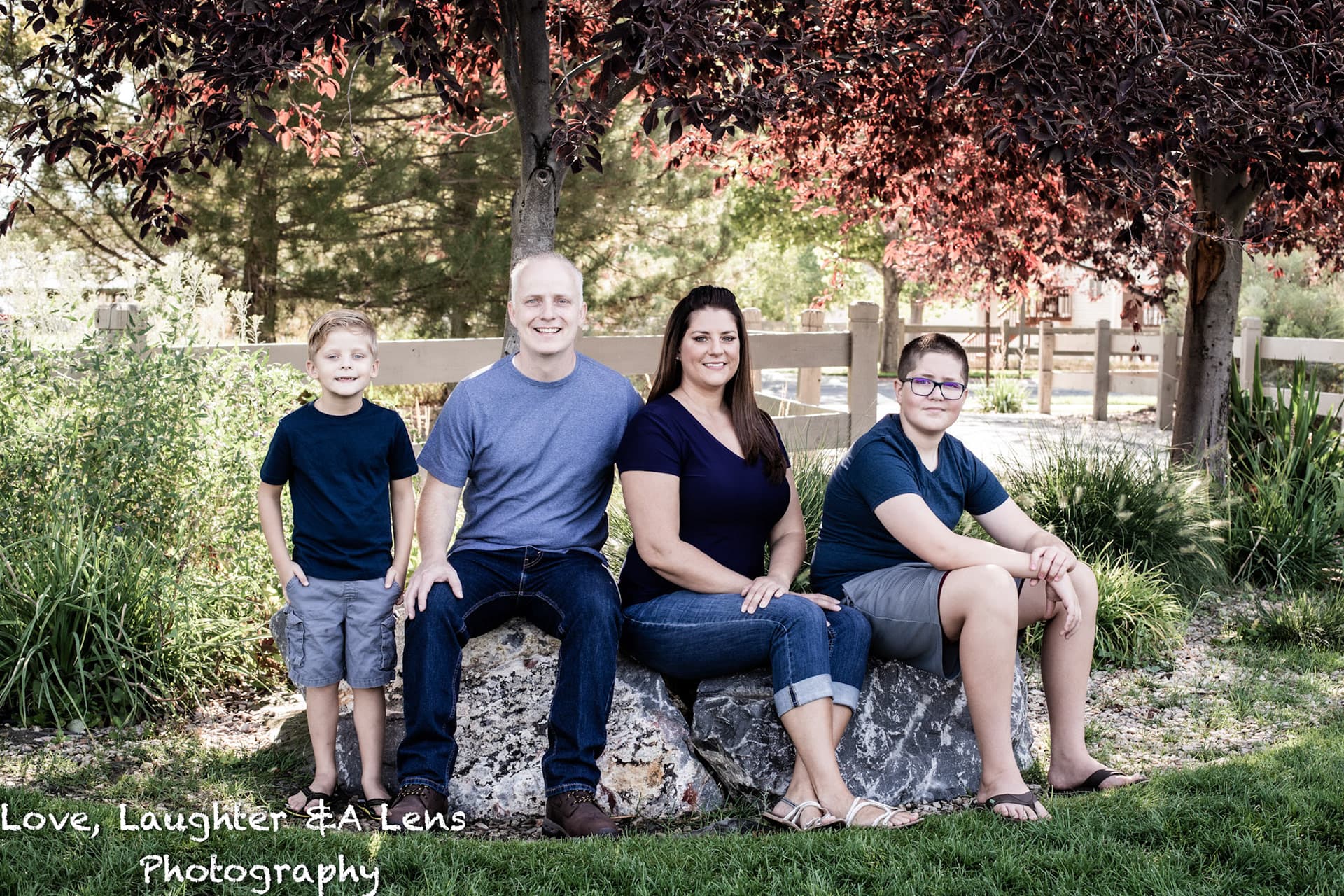 Family of five sitting on a boulder in a garden