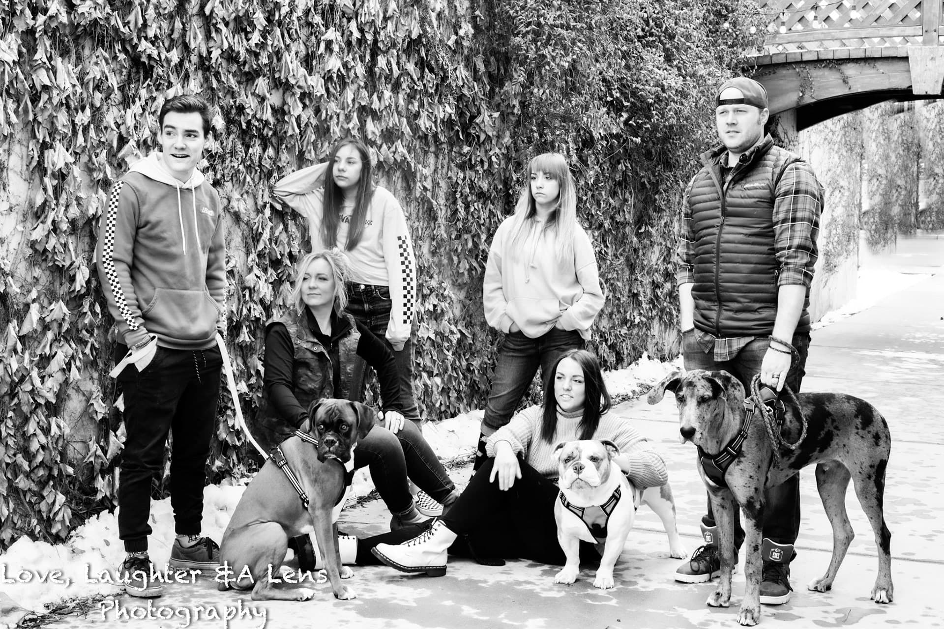 Black-and-white family photo with three dogs