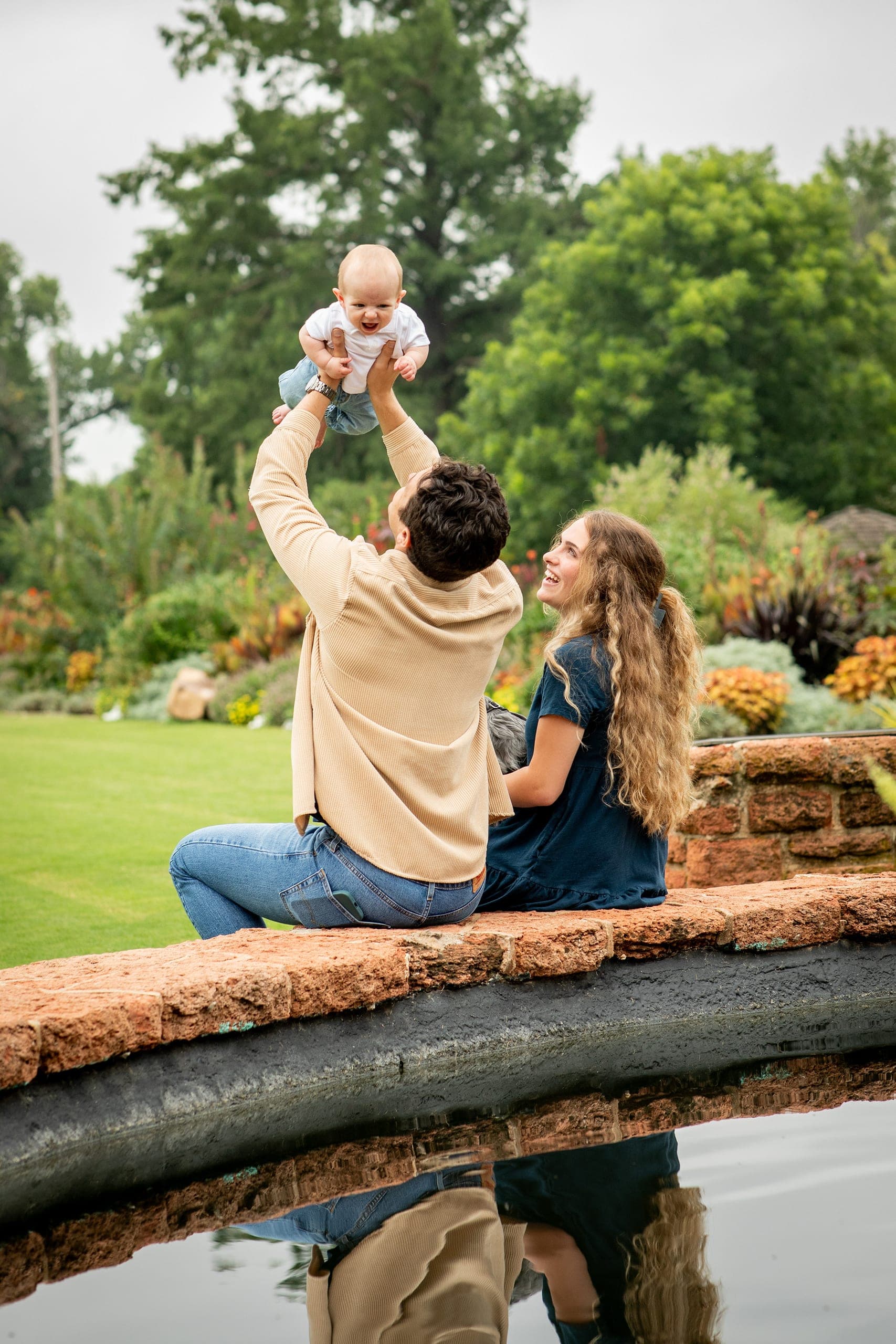 Parent lifting a baby into the air in a garden