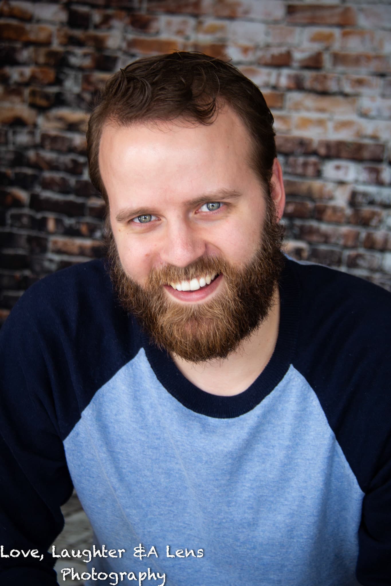 Smiling bearded man in front of a brick wall