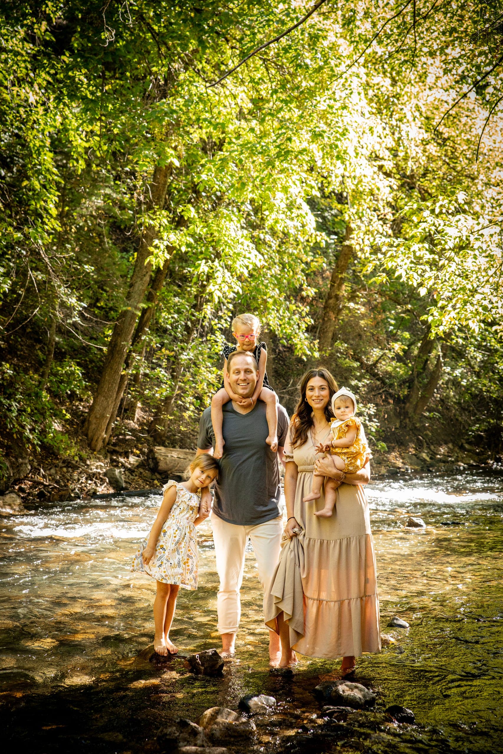 Family standing in a shallow creek surrounded by trees