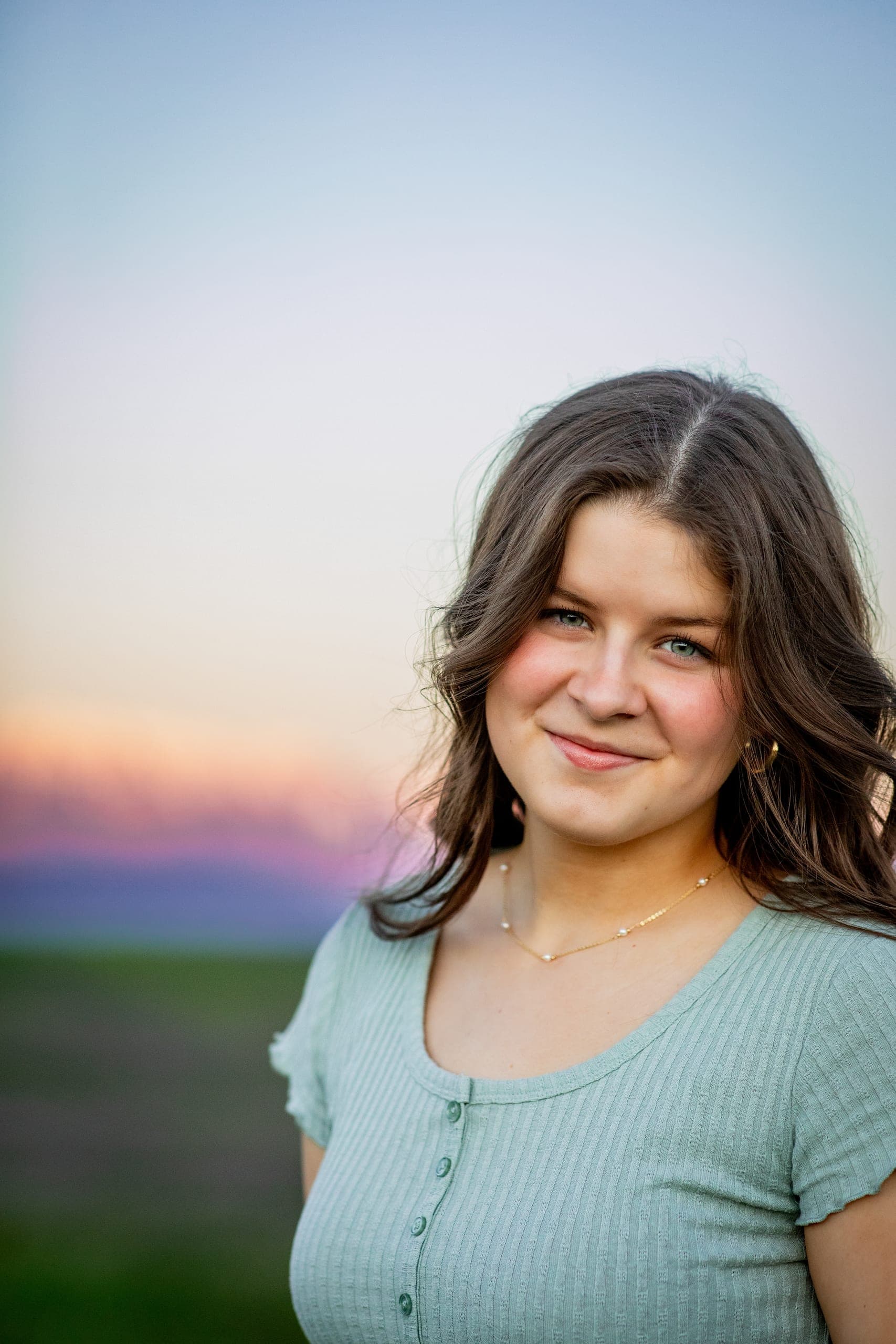 Senior portrait against a pink and blue sunset sky