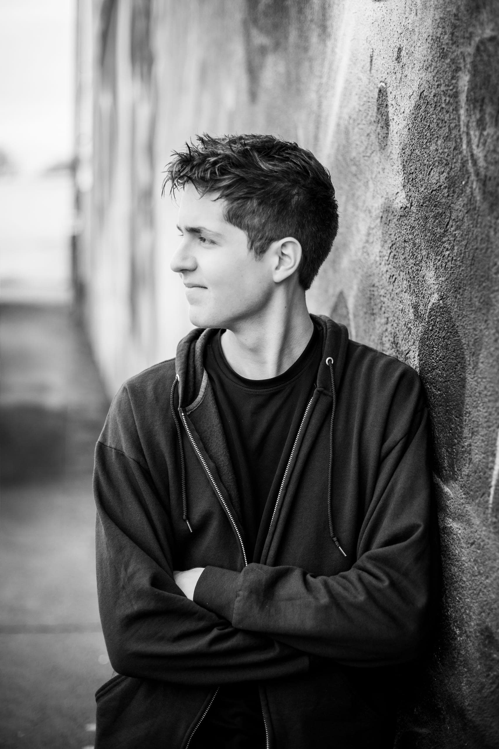 Black-and-white senior portrait leaning against a wall