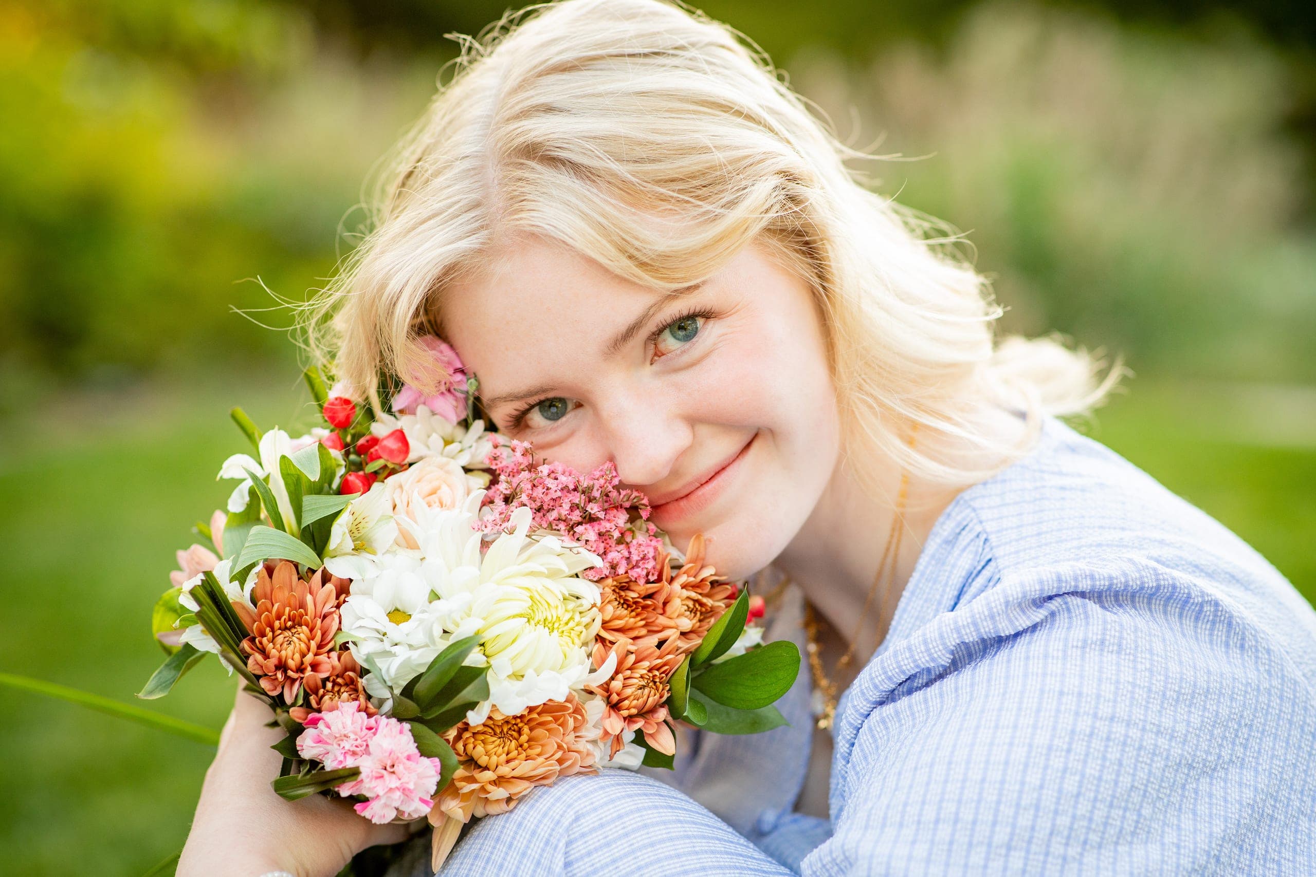 Senior holding a bouquet of flowers in the grass