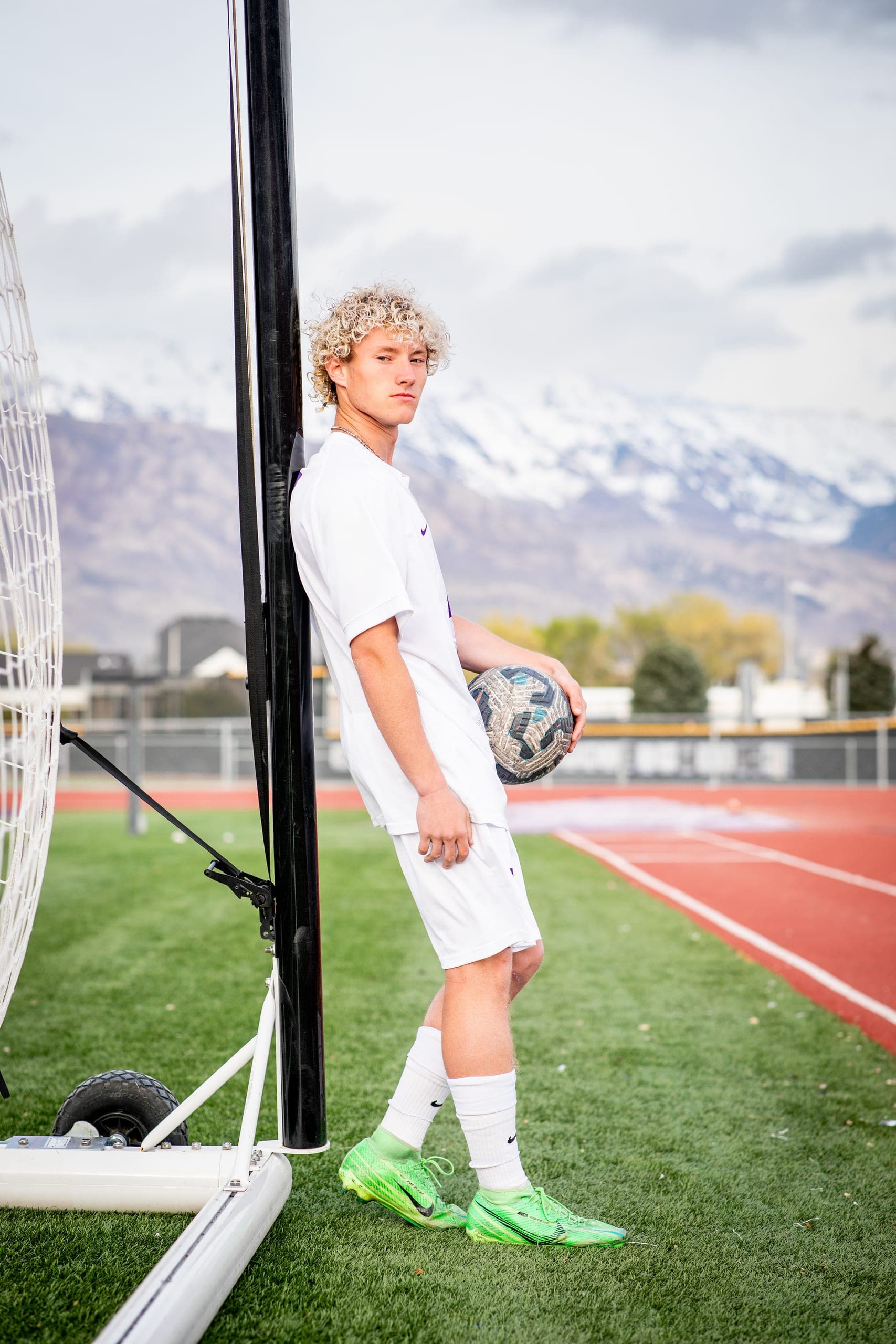Senior soccer player leaning on a goal post with snowy mountains behind