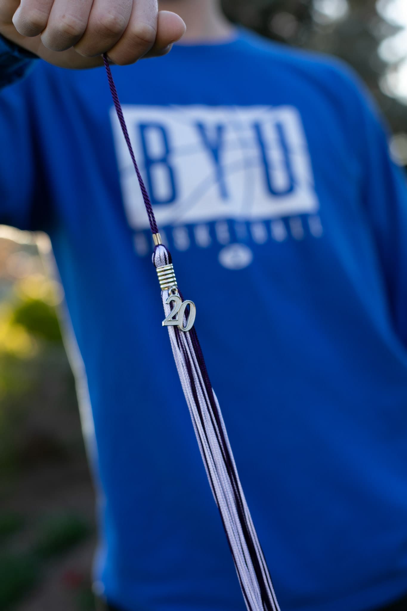 Graduation tassel held in front of a BYU shirt