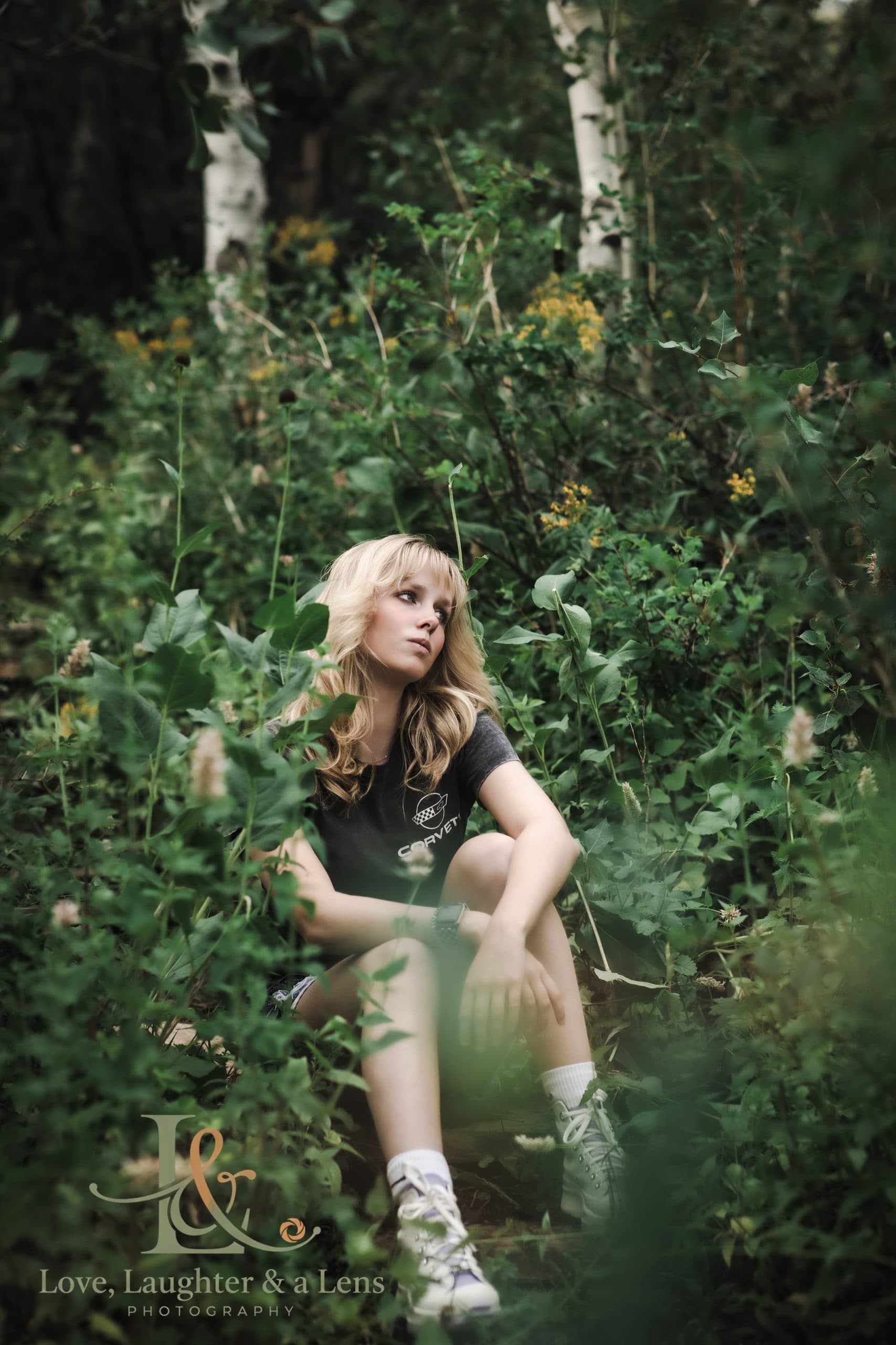 Senior sitting among tall green plants and aspen trees