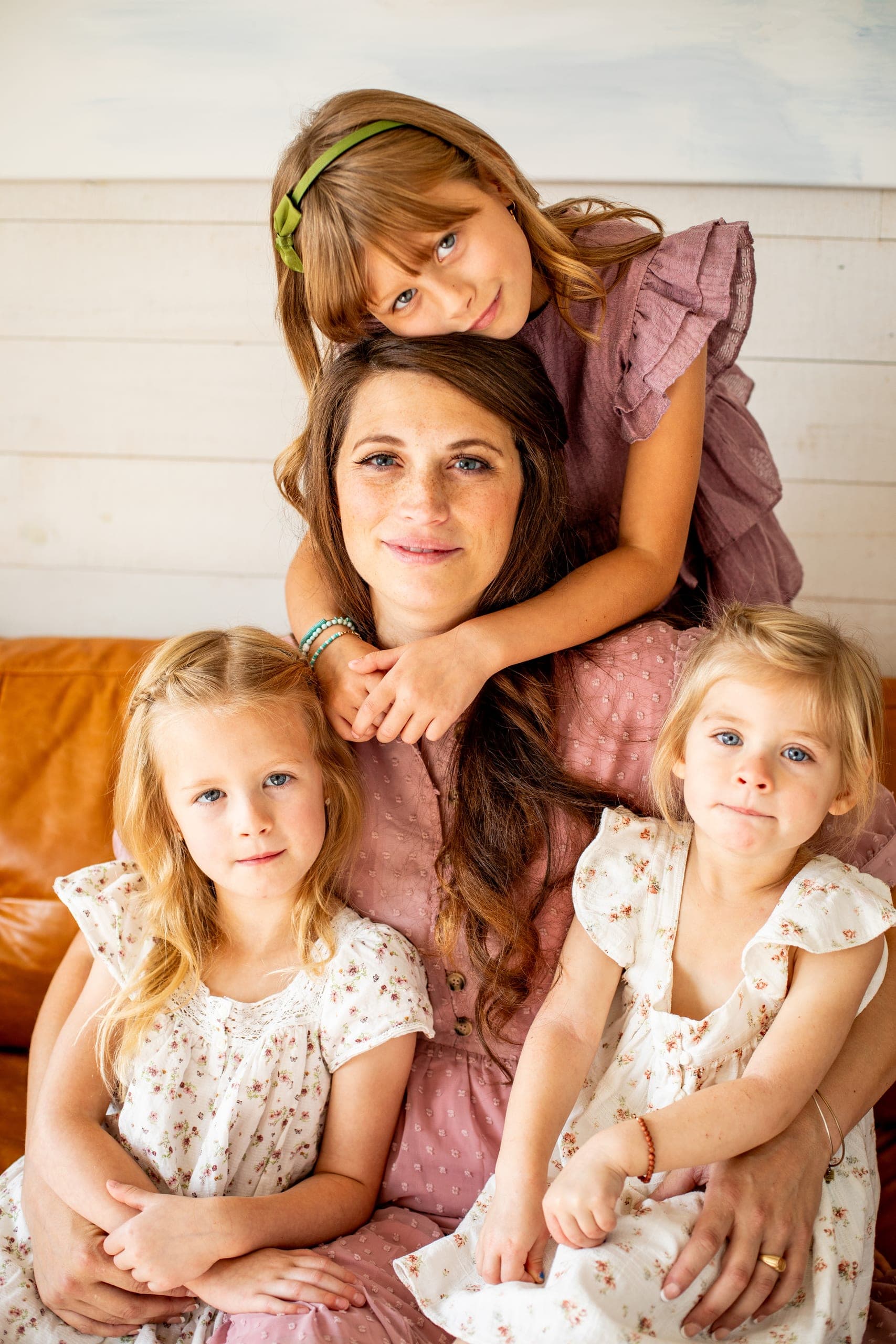 Parent and three young kids snuggled on a couch