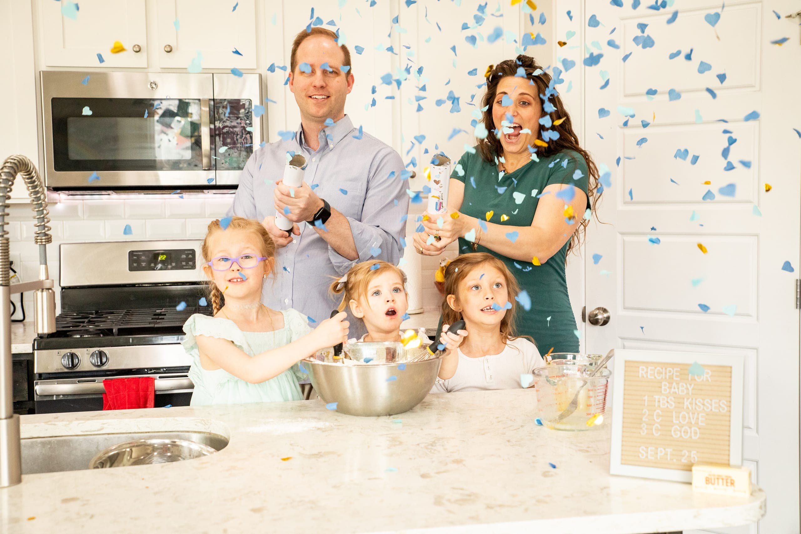 Family celebrating with blue confetti in their kitchen