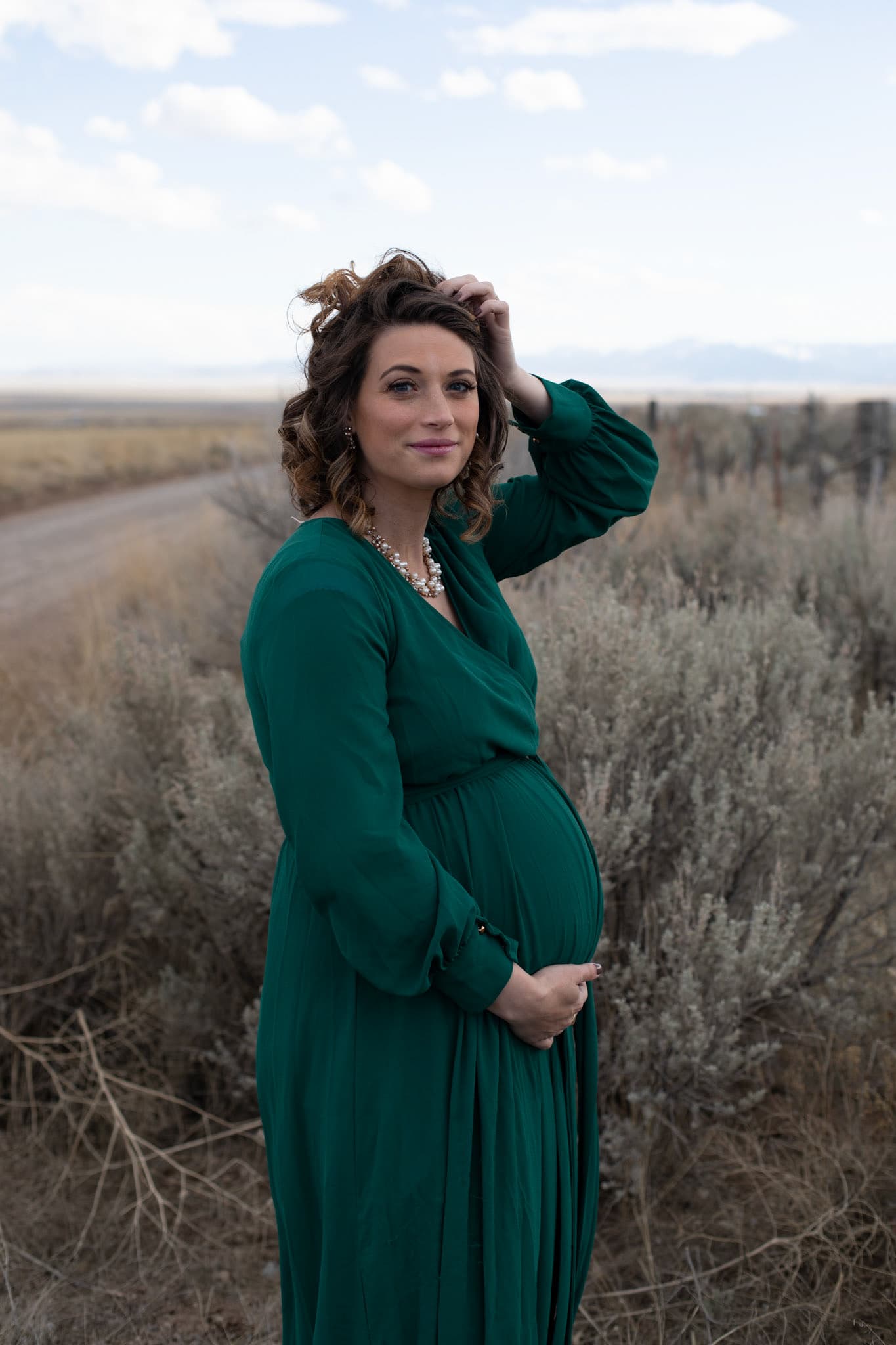 Maternity portrait in a green dress in a sagebrush field