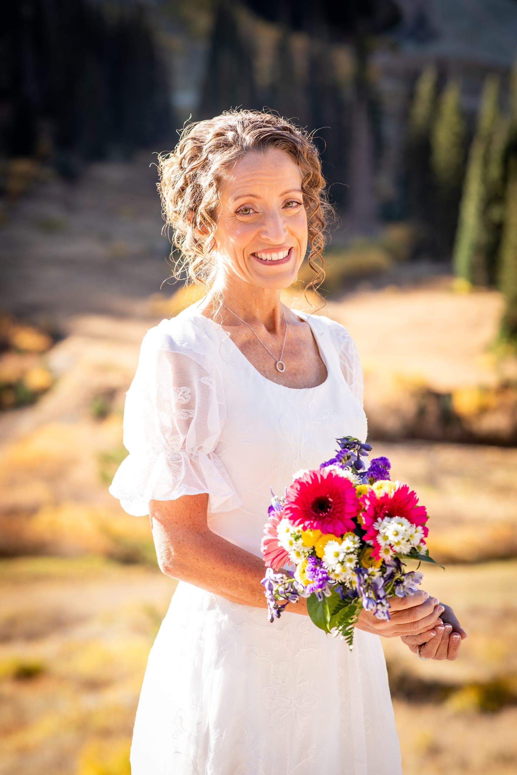 Bride holding a colorful bouquet in the mountains in fall