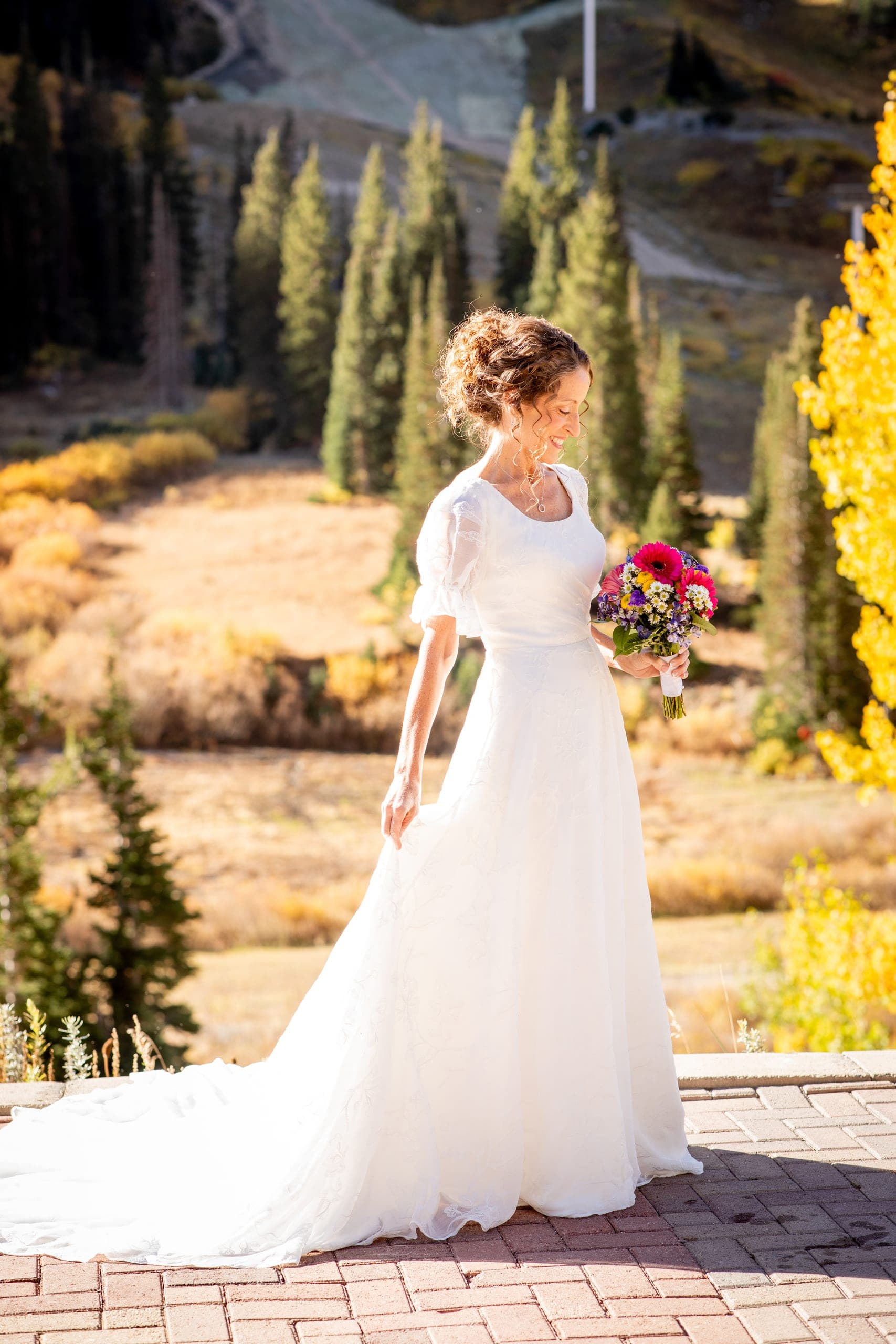 Bride in a long gown on a mountain patio surrounded by fall color