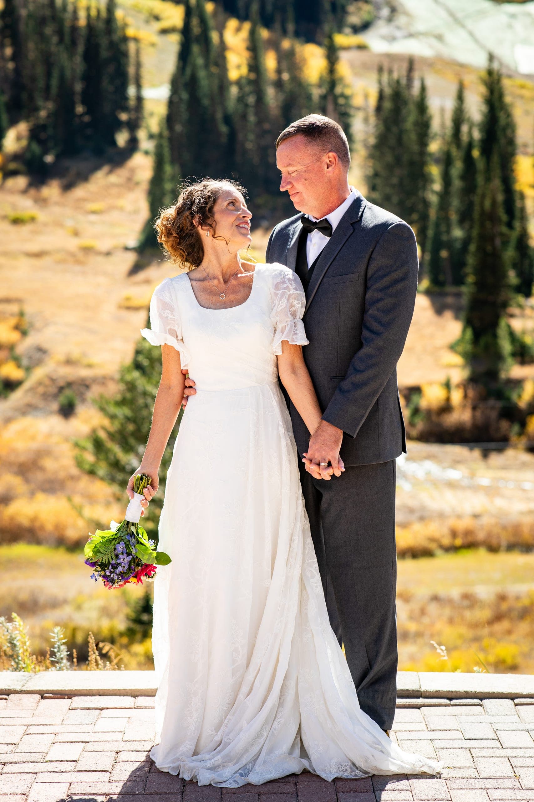 Bride and groom holding hands in the mountains