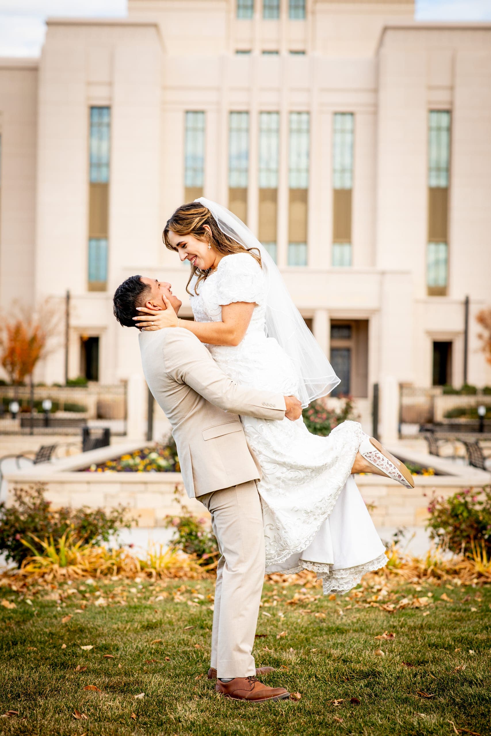 Groom lifting the bride in front of a temple