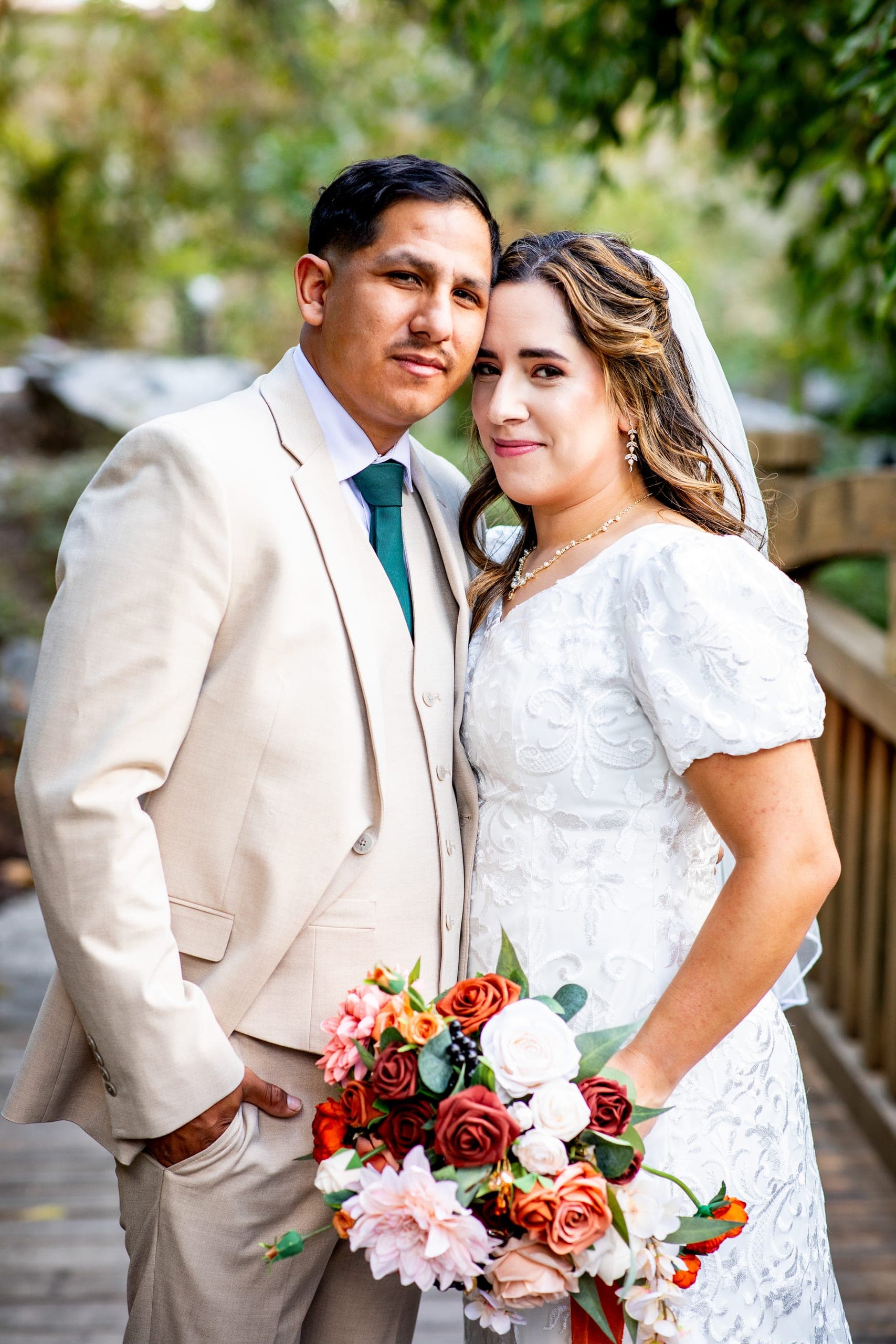 Bride and groom by a wooden bridge holding a bouquet