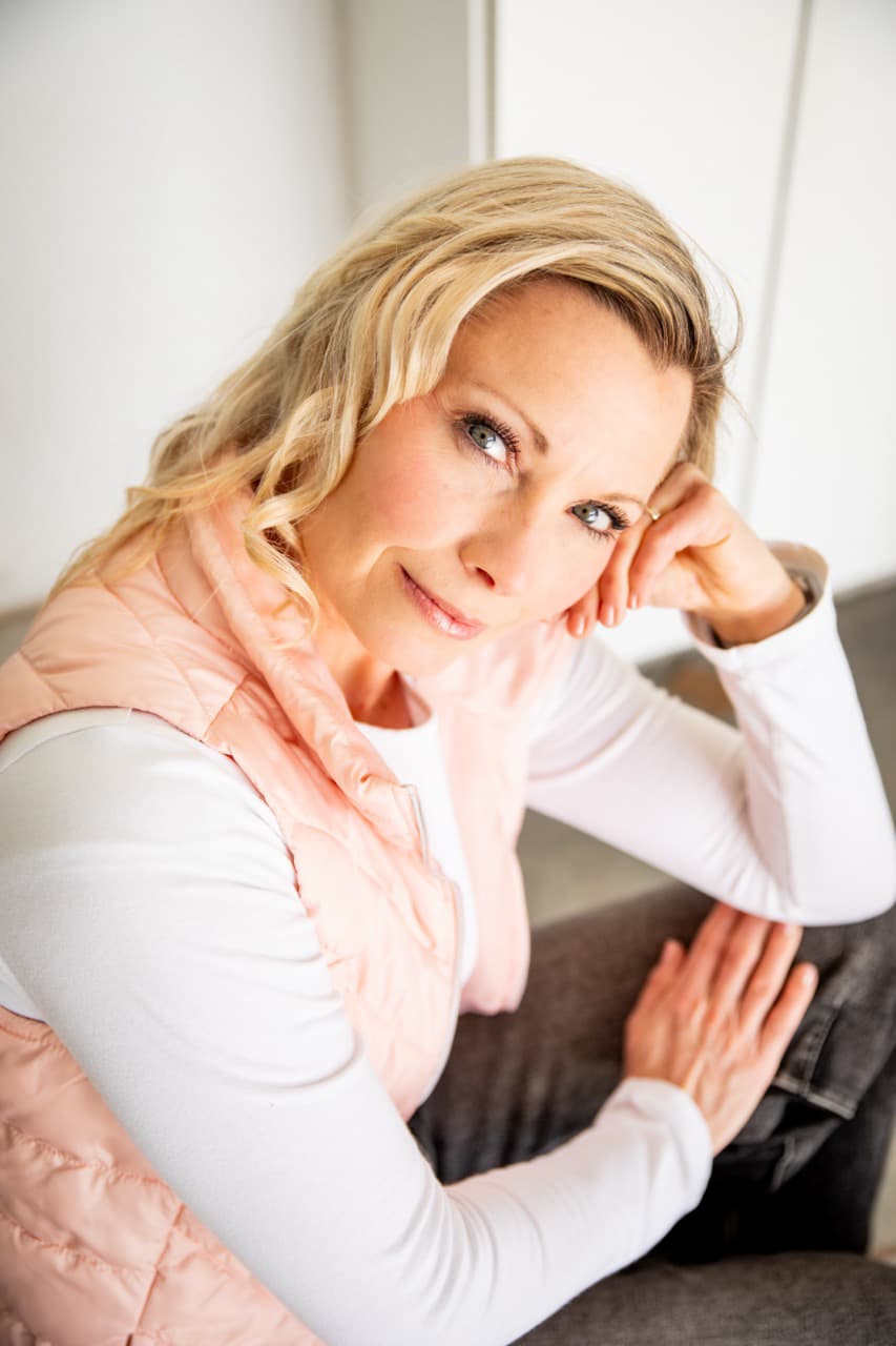 Woman in a pink vest posing in soft window light